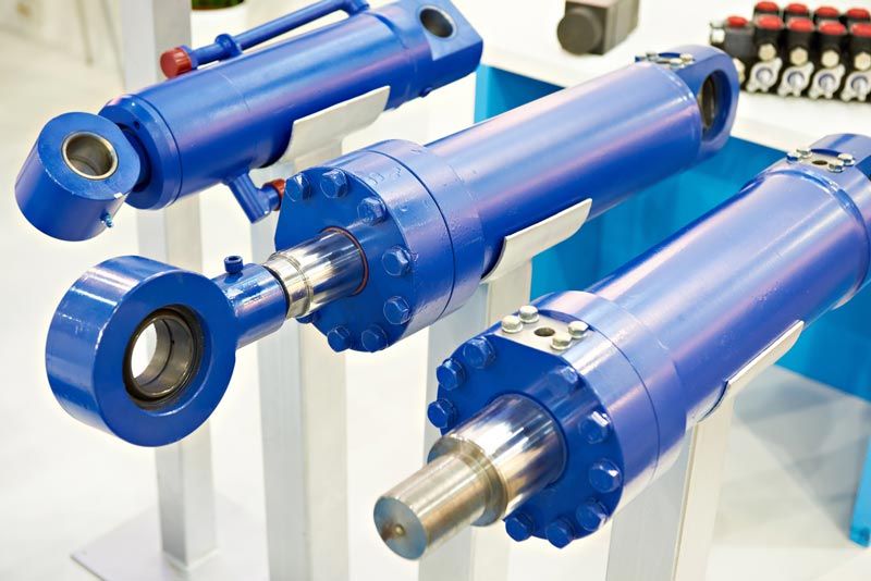 A group of blue hydraulic cylinders are sitting on a table.