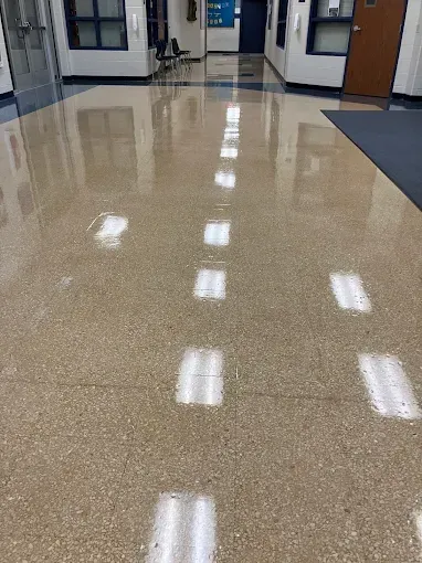 Polished beige floor reflecting overhead lights in a school hallway.
