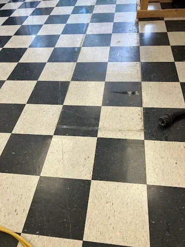 Black and white checkered floor tiles, some with wear and dirt, in an interior space.