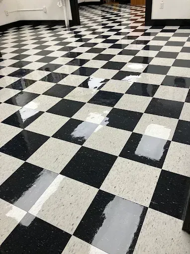 Black and white checkered floor with multiple wet patches reflecting light.