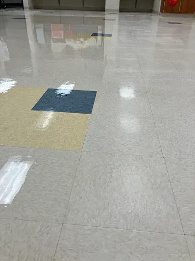 Shiny, reflective gray floor tiles with a yellow and blue square, reflecting overhead lights.
