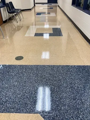 Hallway with shiny tan and blue speckled flooring, and a repeating pattern.