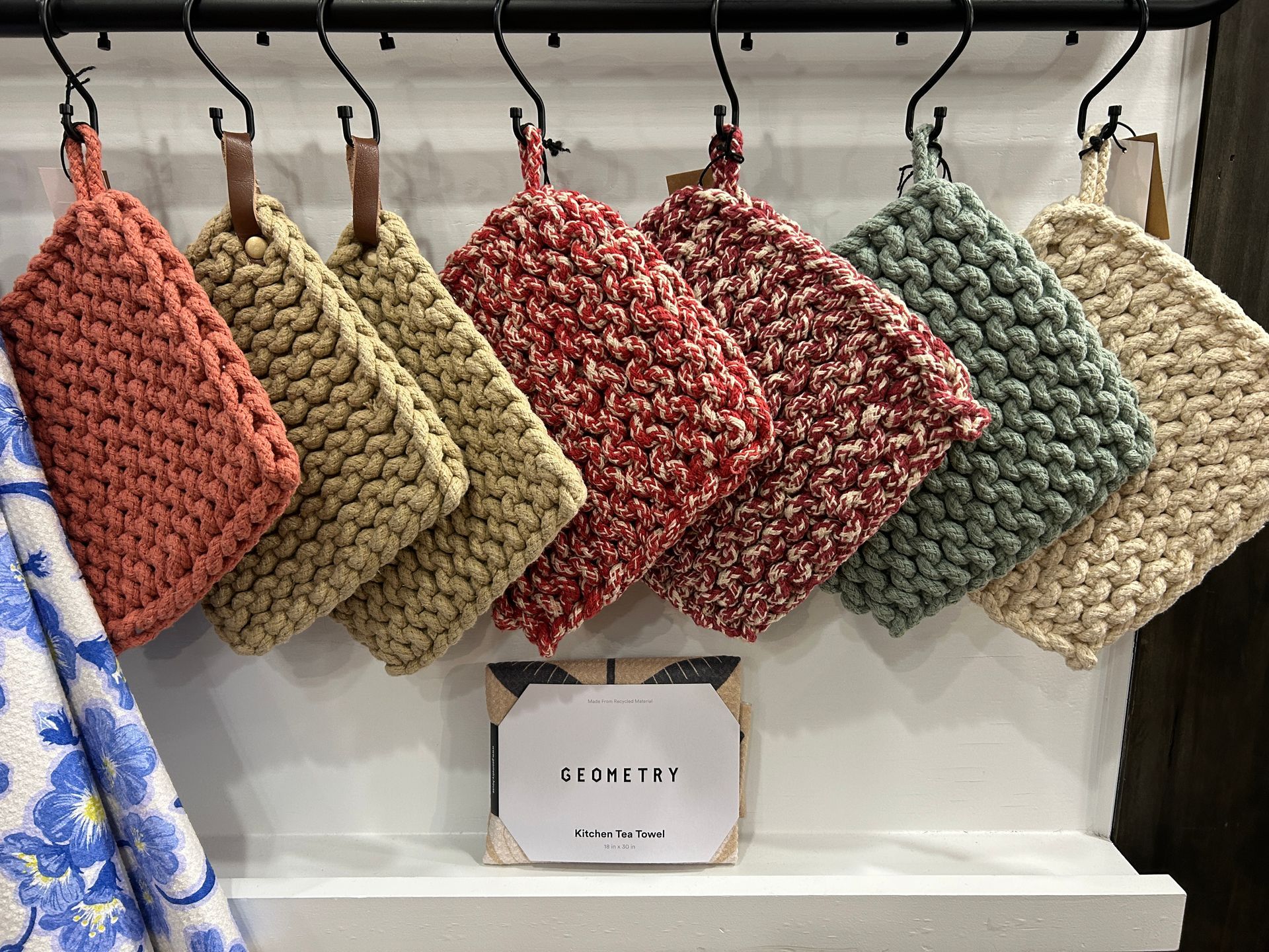 Hanging woven pouches in pink, yellow, red, green, and beige on a display rack