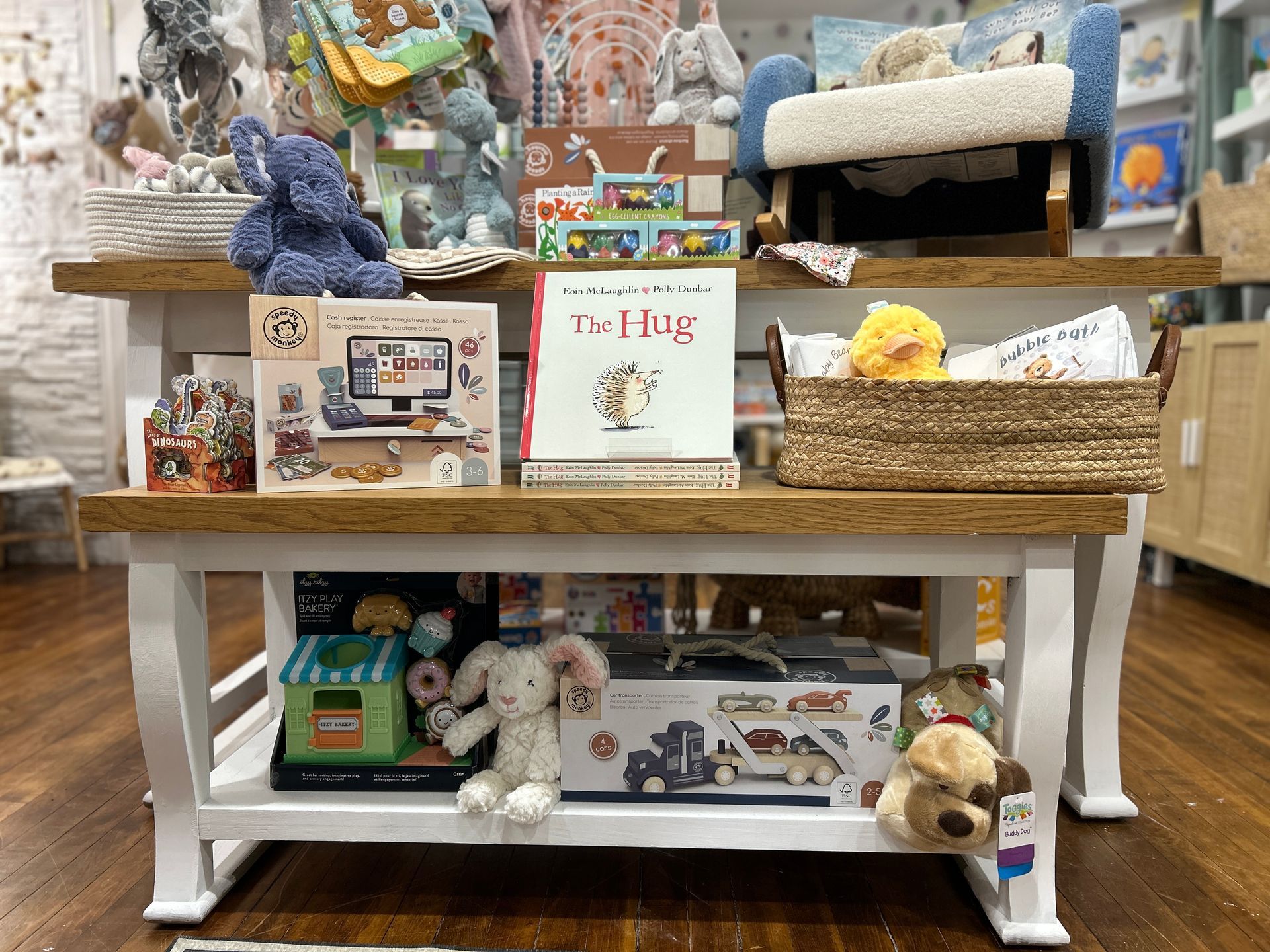 Gift shop display with plush toys, baskets, and a spring-themed sign on a wooden table.