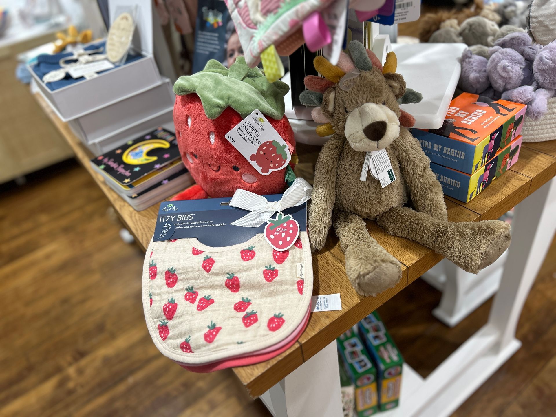 Plush toys and small accessories displayed on a store table, including a brown teddy bear and strawberry-themed items