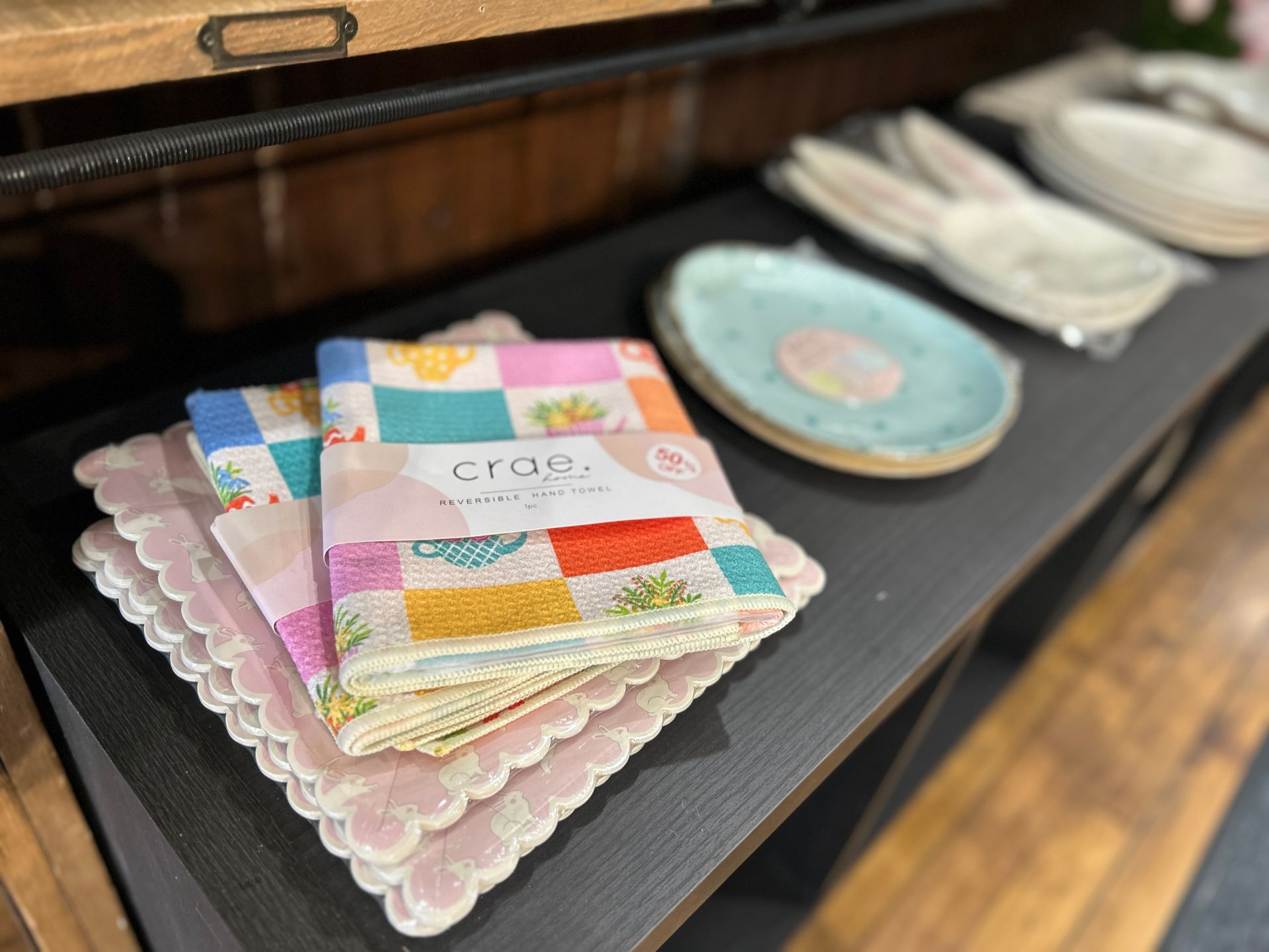 Colorful quilted coasters stacked on a table beside plates and folded linens