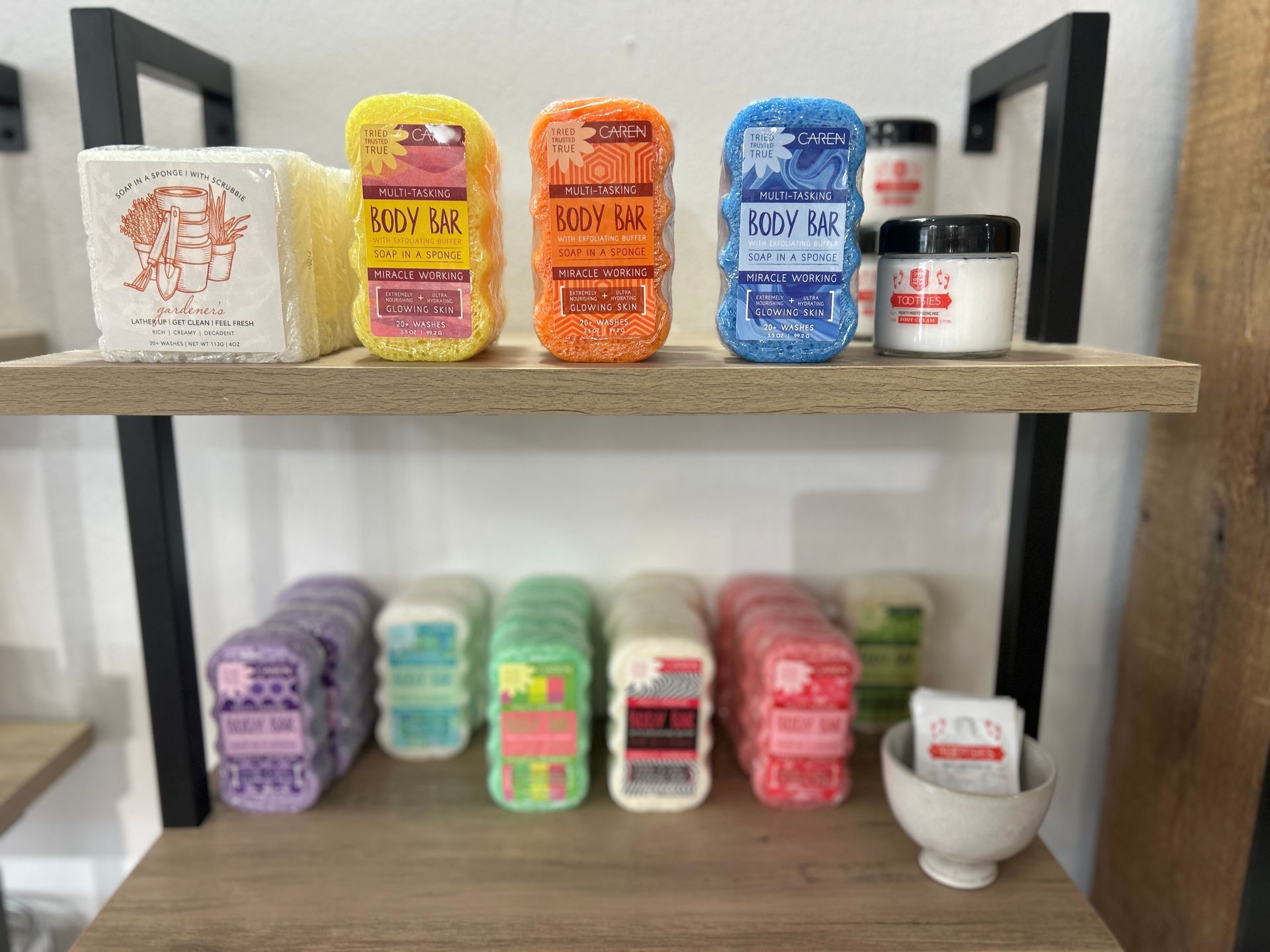 Two-tier shelf of colorful small containers and jars arranged in rows against a white wall
