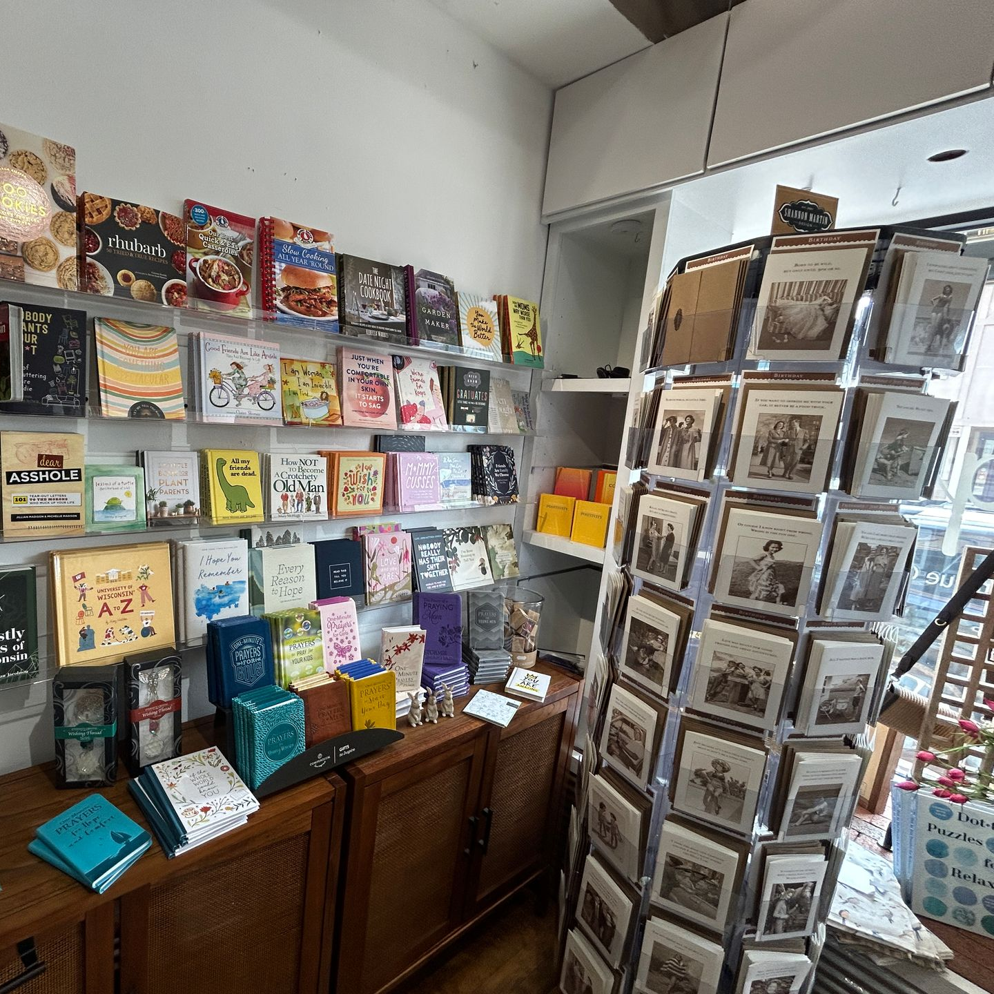 Greeting card and gift shop display with colorful cards and postcards on shelves and a rotating rack.