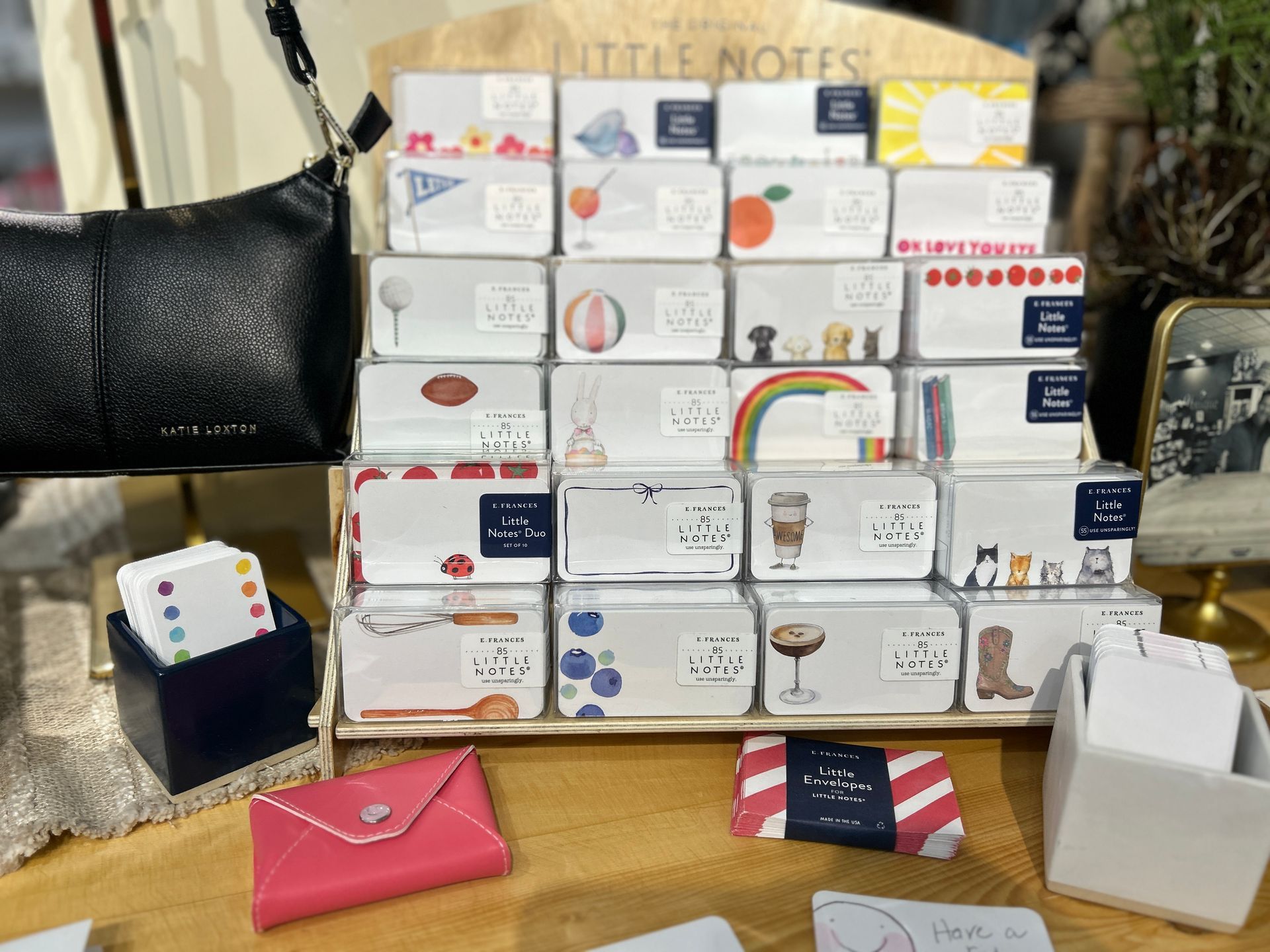 Assorted stationery and business cards displayed on a table, with a pink envelope and small boxes in front.