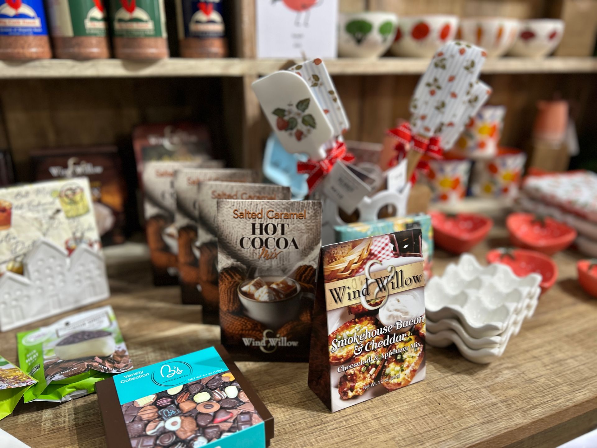 Assorted packaged sweets and gift boxes displayed on a wooden table in a shop.
