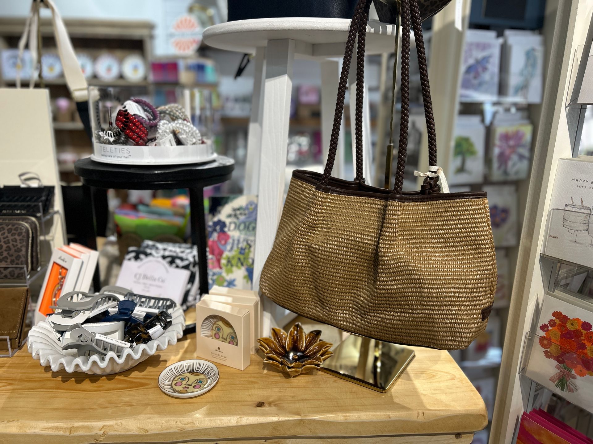Gift basket display with a woven tote, small boxes, and decorative items on a wooden table in a shop