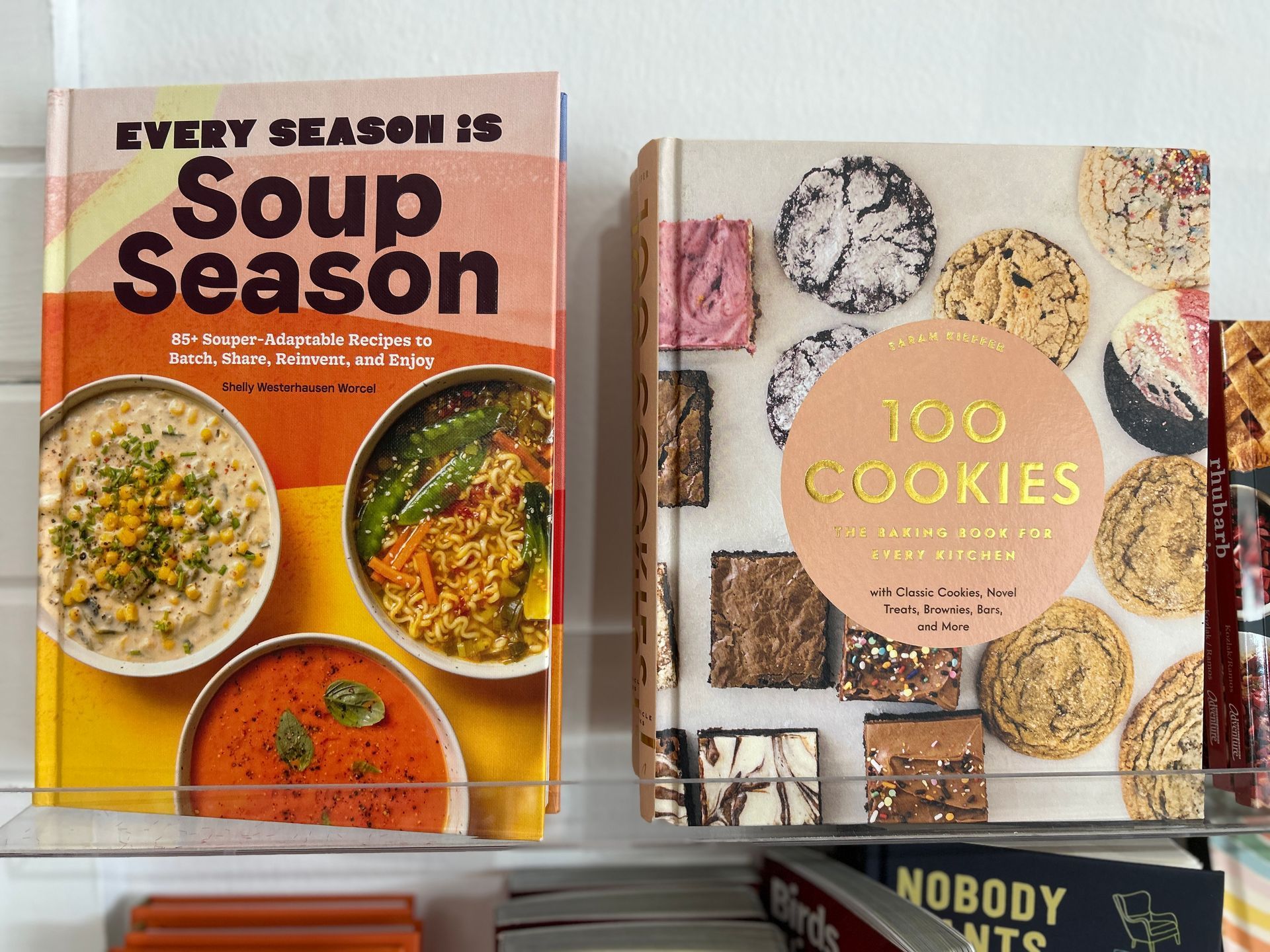 Two cookbooks on a white surface: Every Season Is Soup Season and 100 Cookies, with a third book partly visible below.