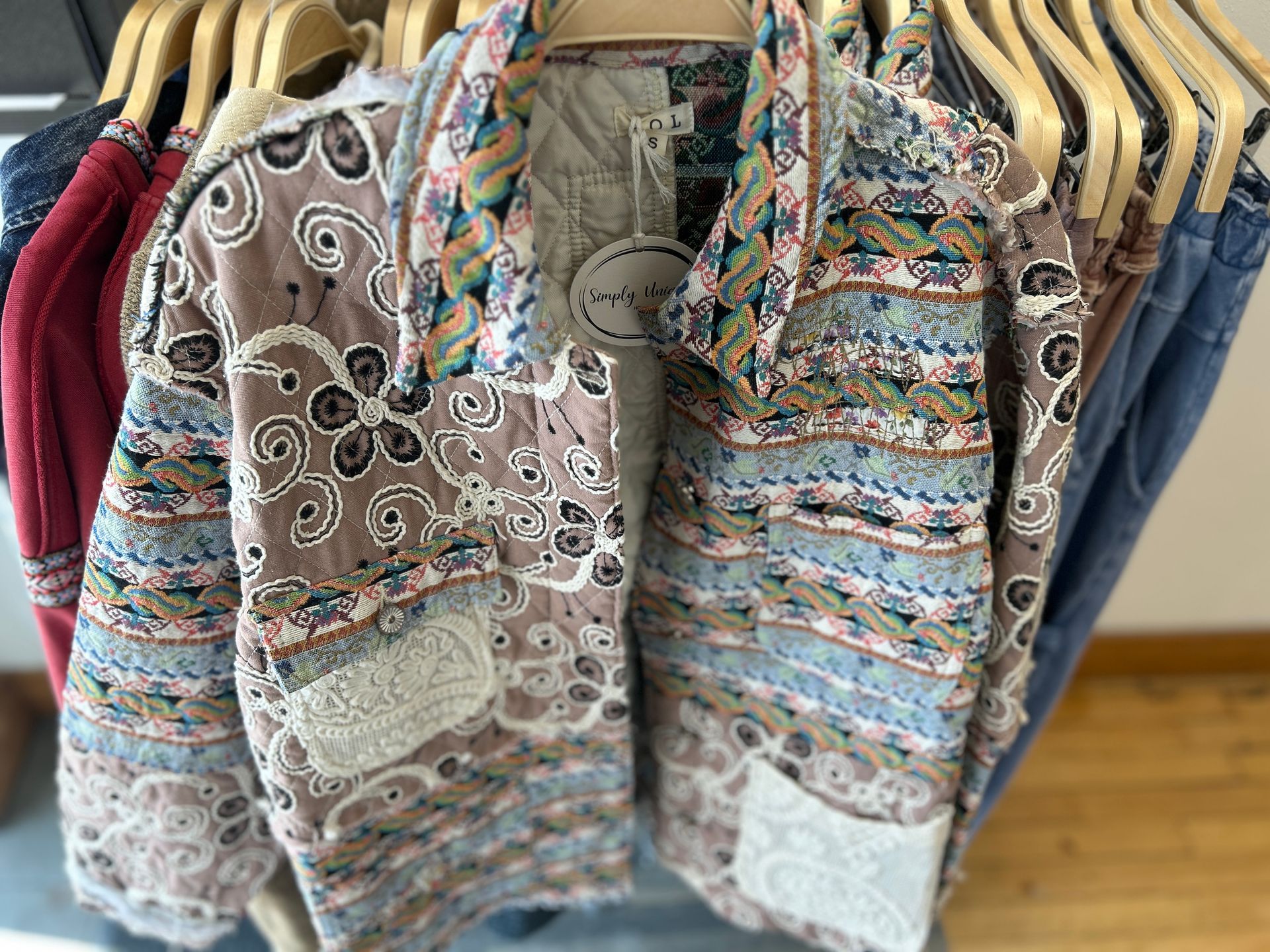 Colorful patterned jackets hanging on wooden hangers in a clothing store rack