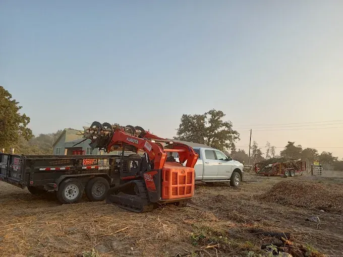 White pickup and red utility trailer on a dirt road at sunrise with smoke in the background