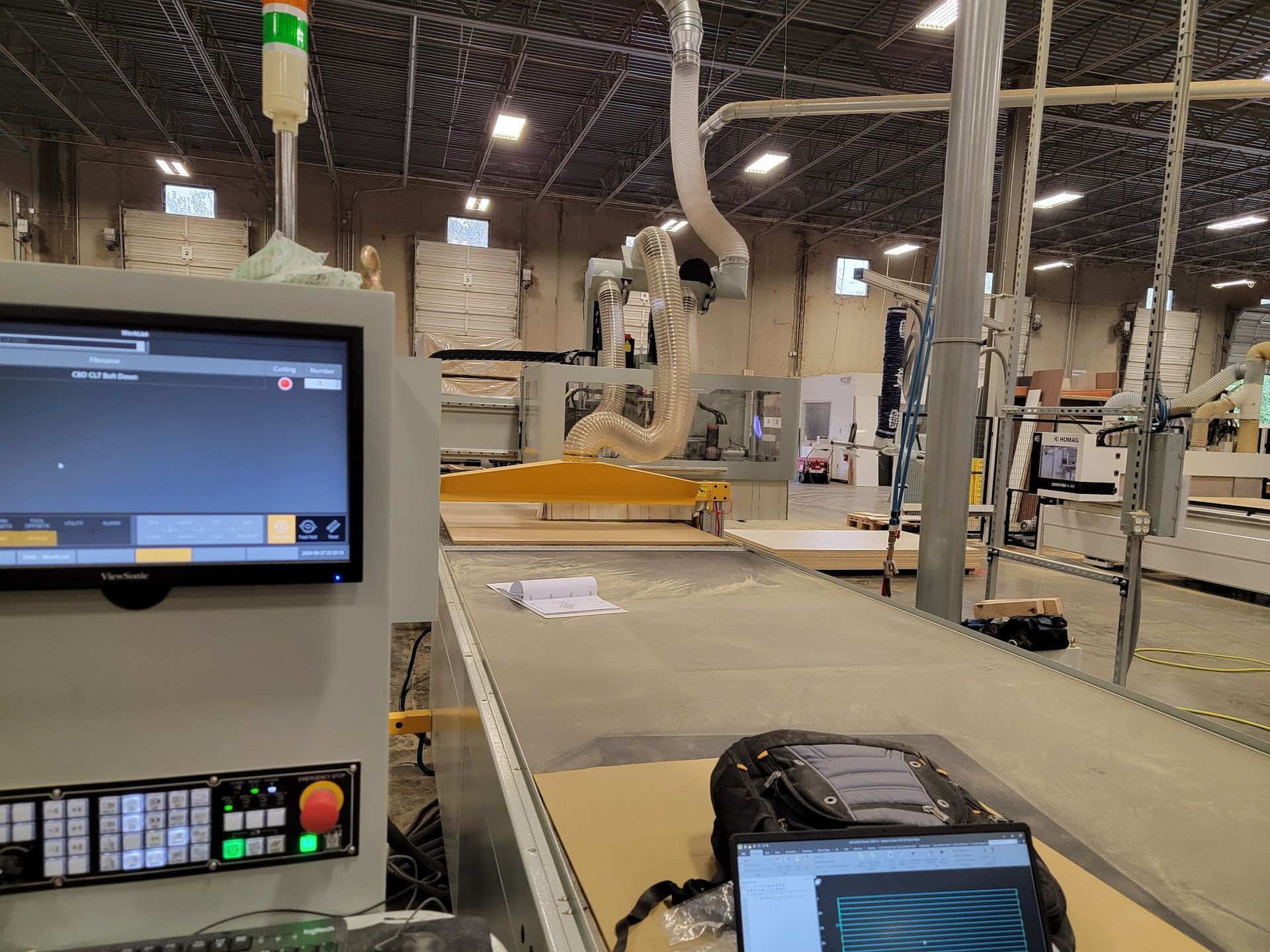 A computer monitor is sitting on a table in a factory next to a laptop.