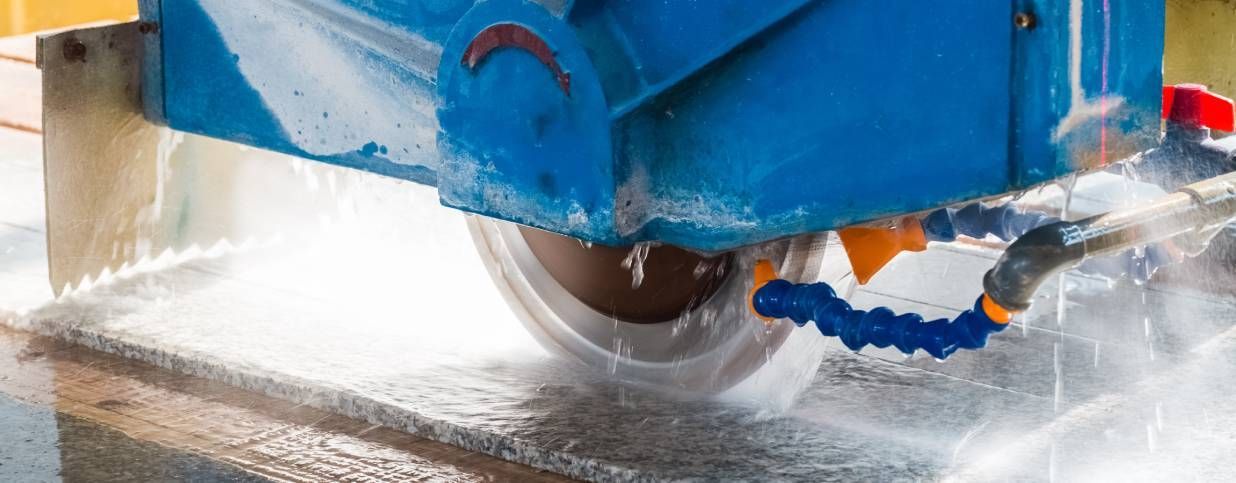 Circular saw cutting a wet stone slab with water cooling system.
