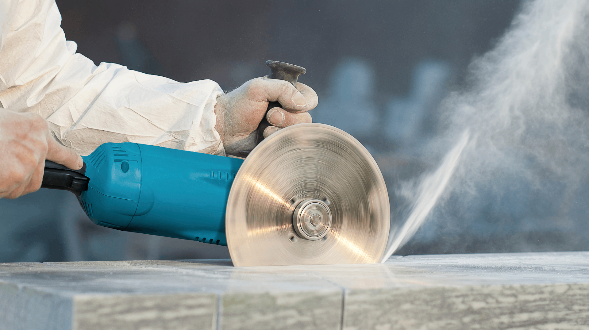 Worker using handheld circular saw to cut a stone slab