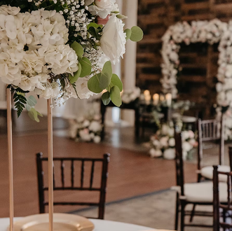White floral wedding decor with chairs and an arch in a warm indoor venue