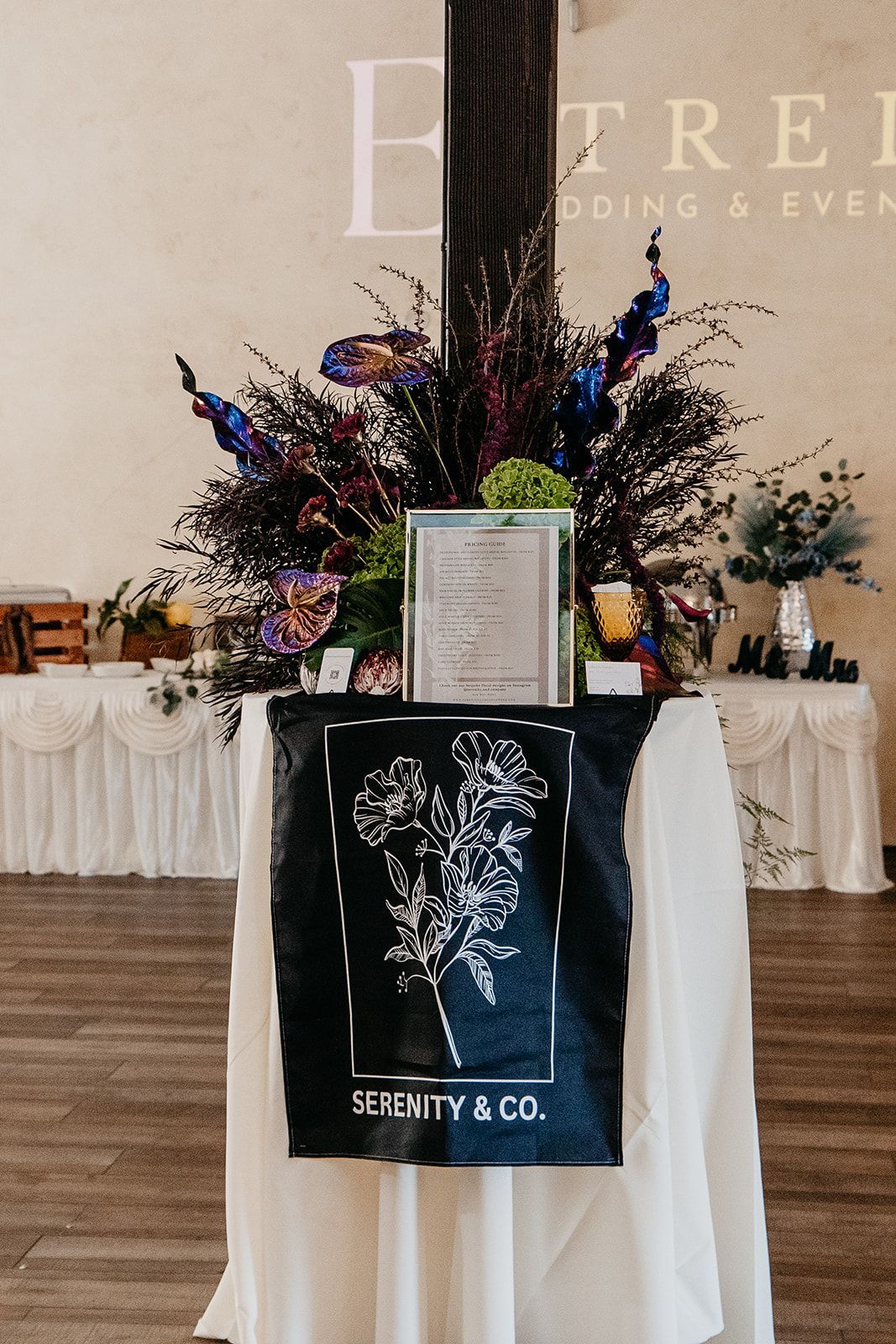 Decorated memorial display with flowers, candles, and framed tribute on draped table