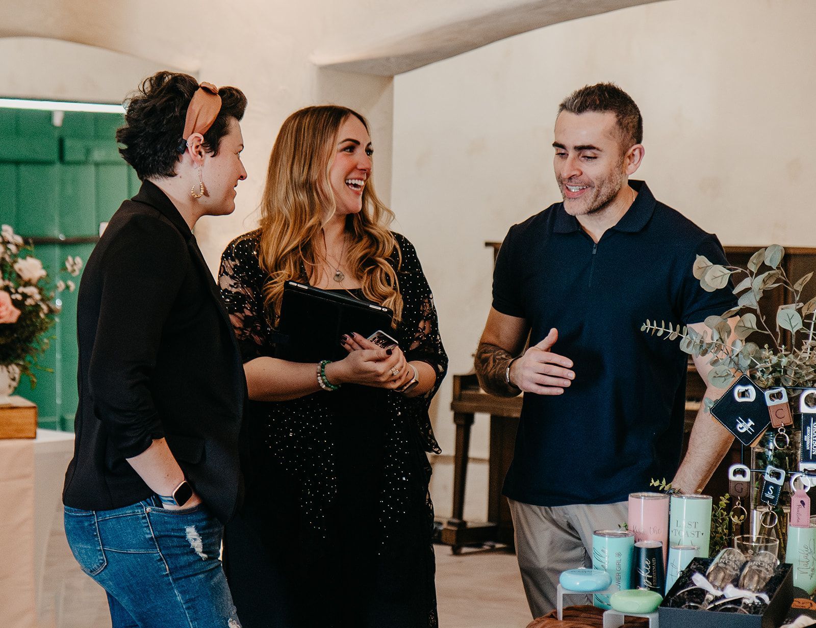 Three people chatting at a market stall with candles and handmade items
