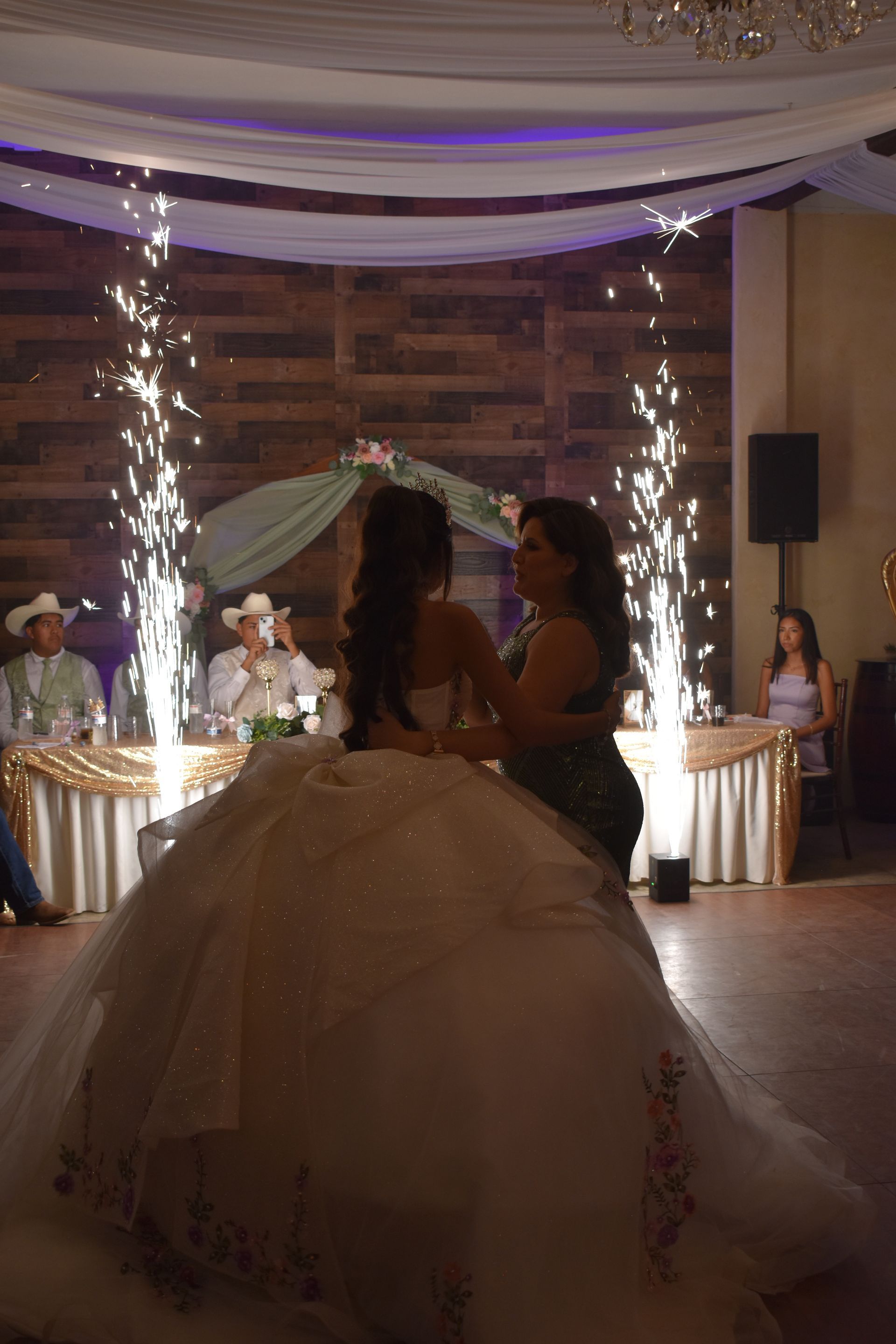 Bride and groom silhouetted in wedding dance under sparkling light columns in a decorated hall