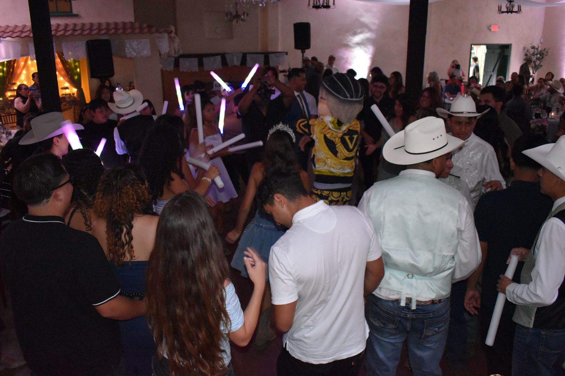 Crowded indoor party with people dancing under colorful lights and hats