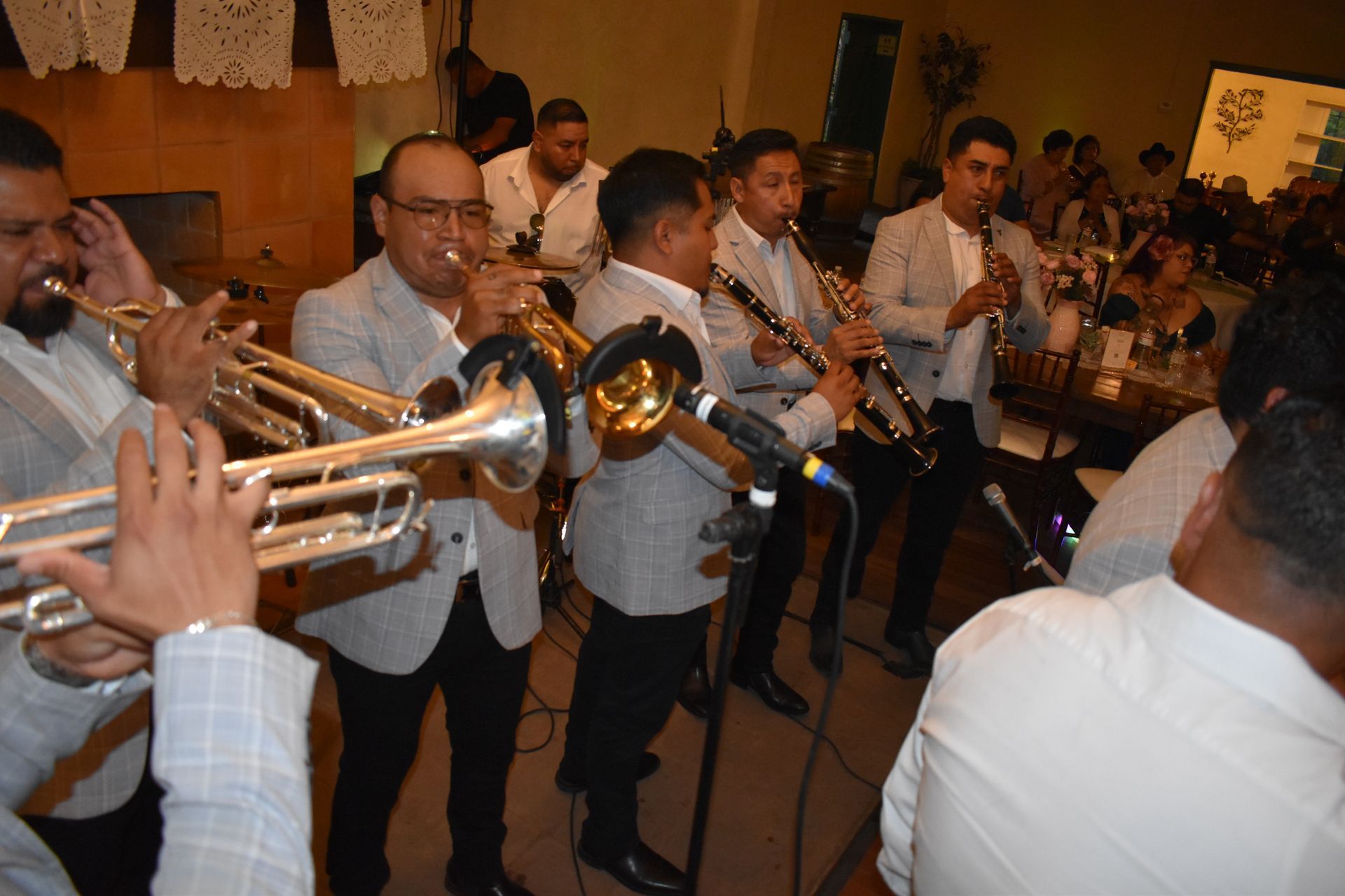 Brass band musicians playing trumpets and saxophones at an indoor event