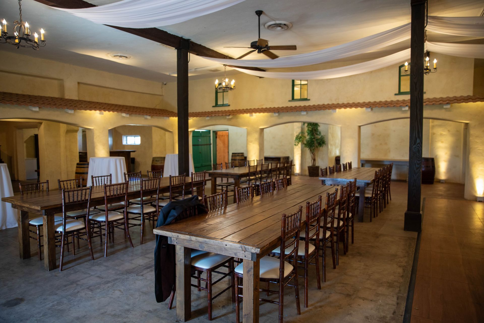 Empty banquet hall with rows of wooden chairs and tables under warm ceiling lights.