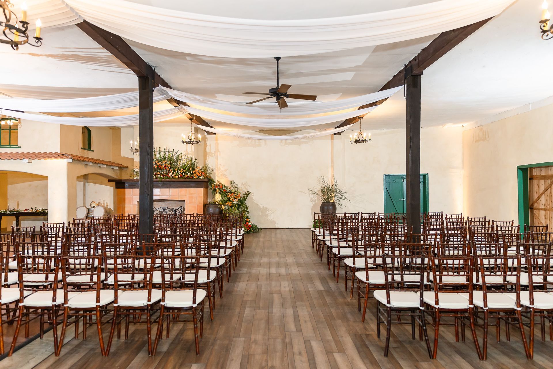 Rows of brown chairs in a decorated event hall with white draped ceiling and wooden floor