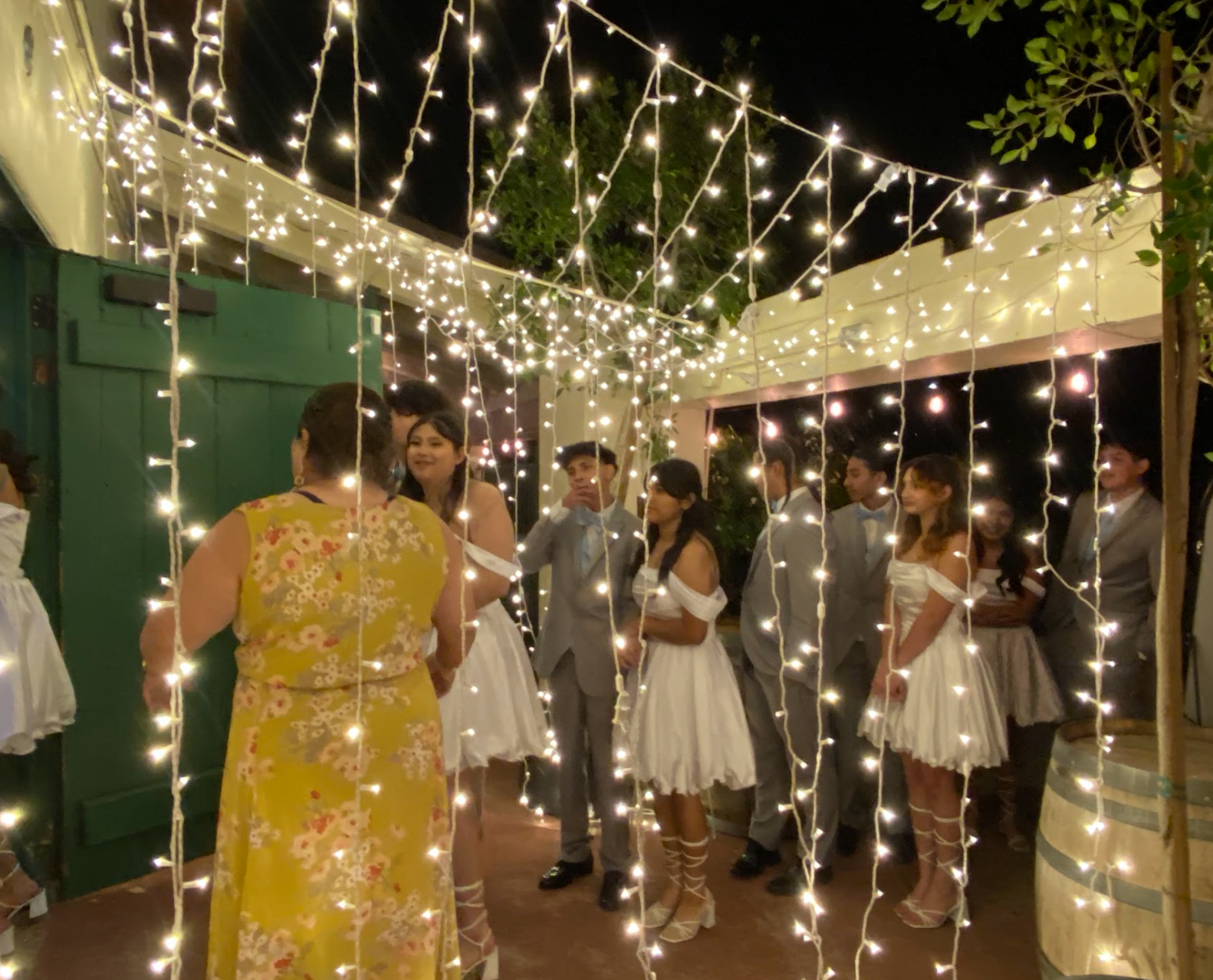 Guests mingle under string lights at a nighttime outdoor party on a patio.