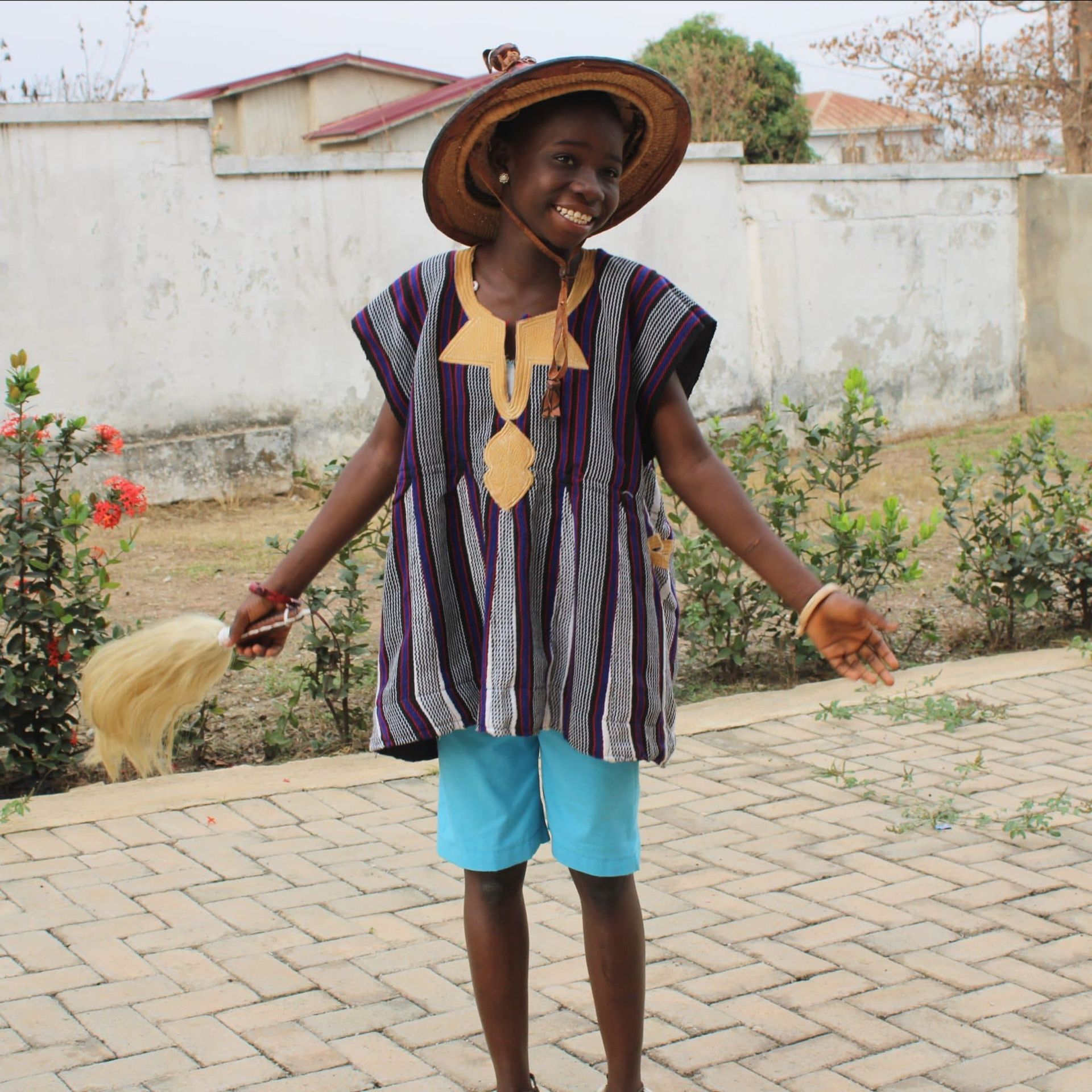 A woman wearing a hat and a striped shirt is standing on a brick sidewalk