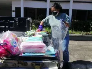A woman wearing a mask is loading supplies into a truck.
