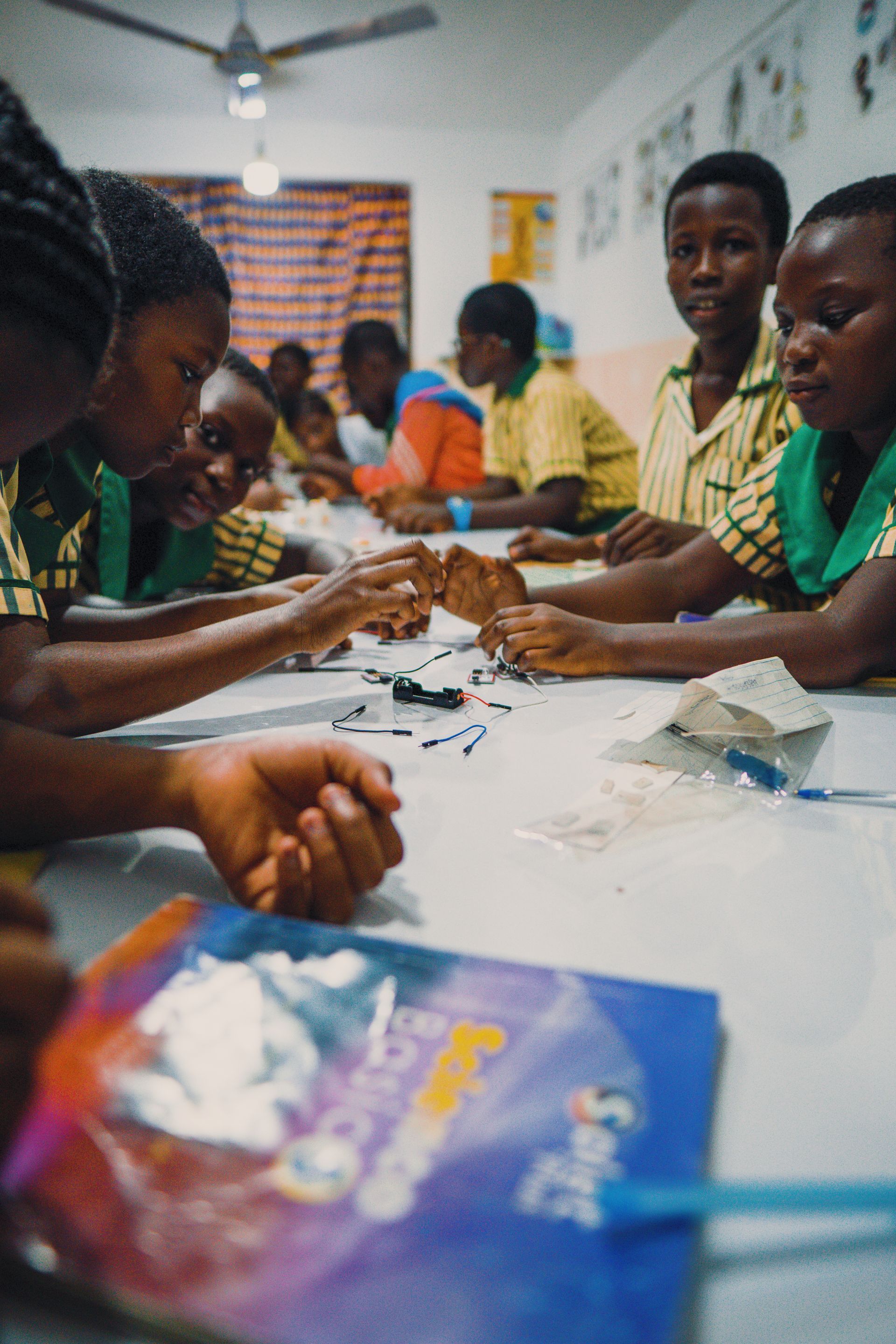 A group of children are sitting at a table in a classroom.