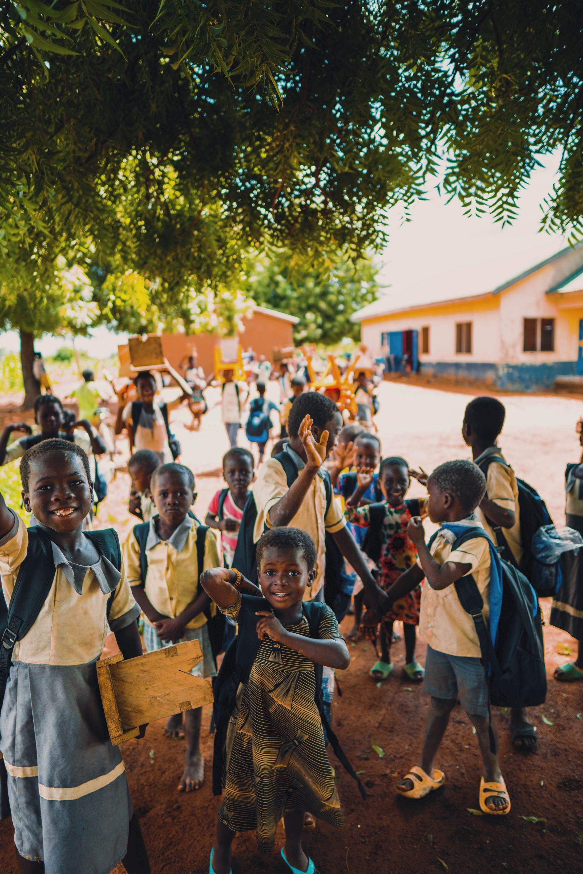 A group of children are standing under a tree holding hands.