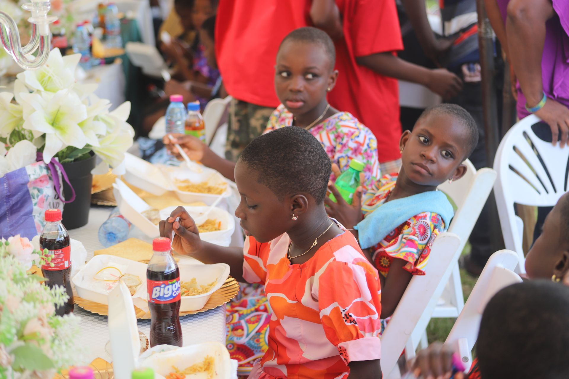 Children seated at a table with food and soda, smiling at a festive gathering