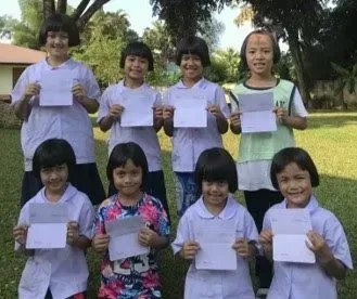 A group of young girls are standing next to each other holding papers.