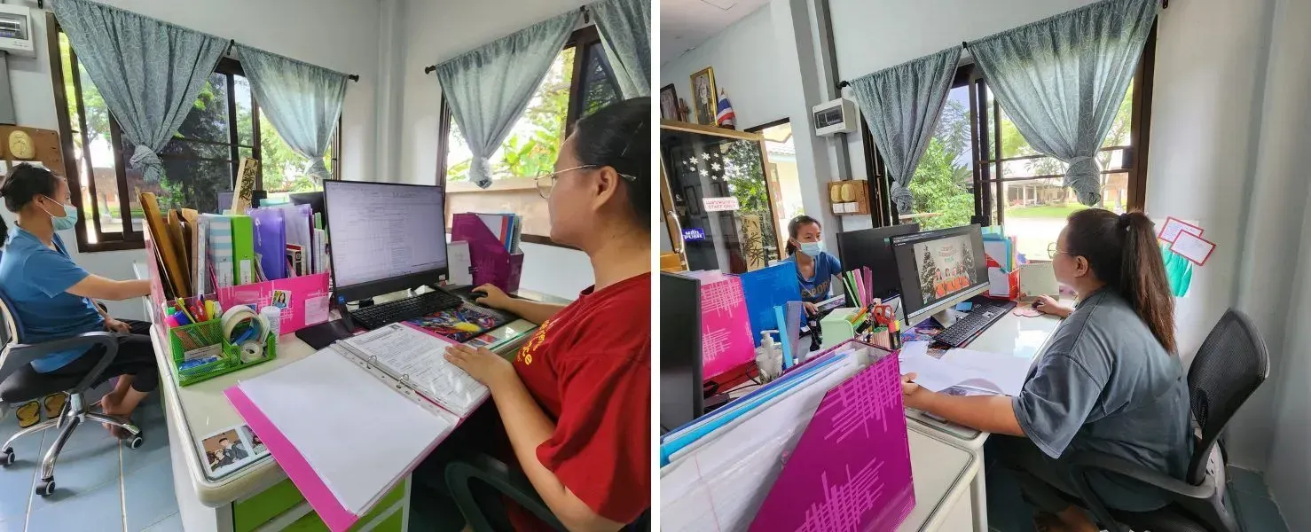 Two women are sitting at desks in front of computers in an office.