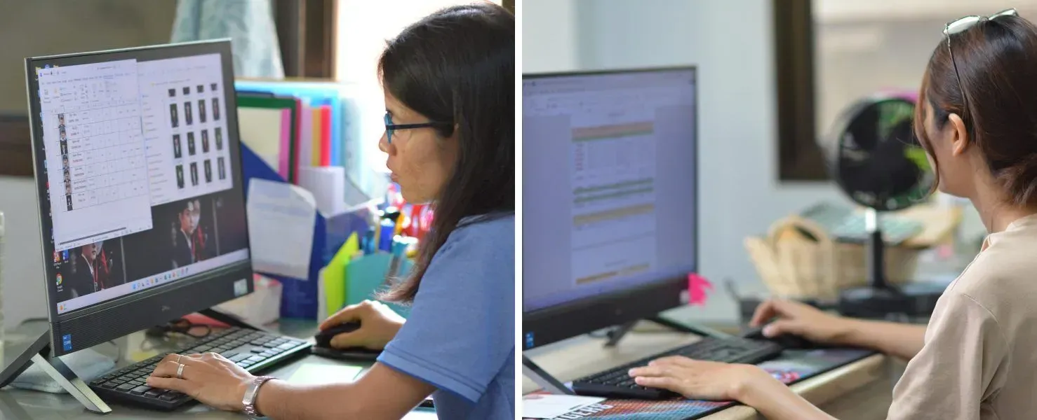 Two women are sitting at a desk working on a computer.