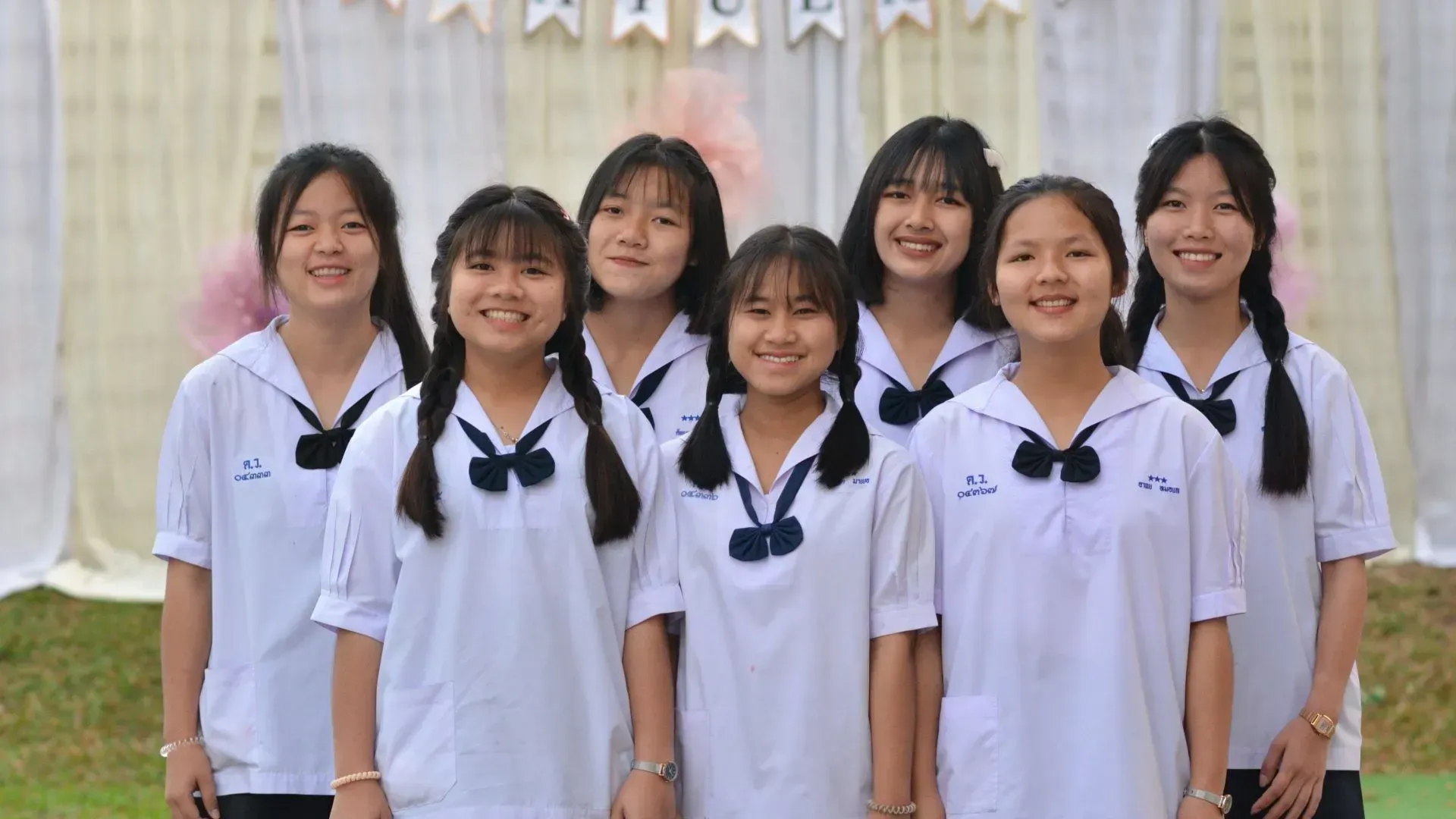 A group of young girls in school uniforms are posing for a picture.