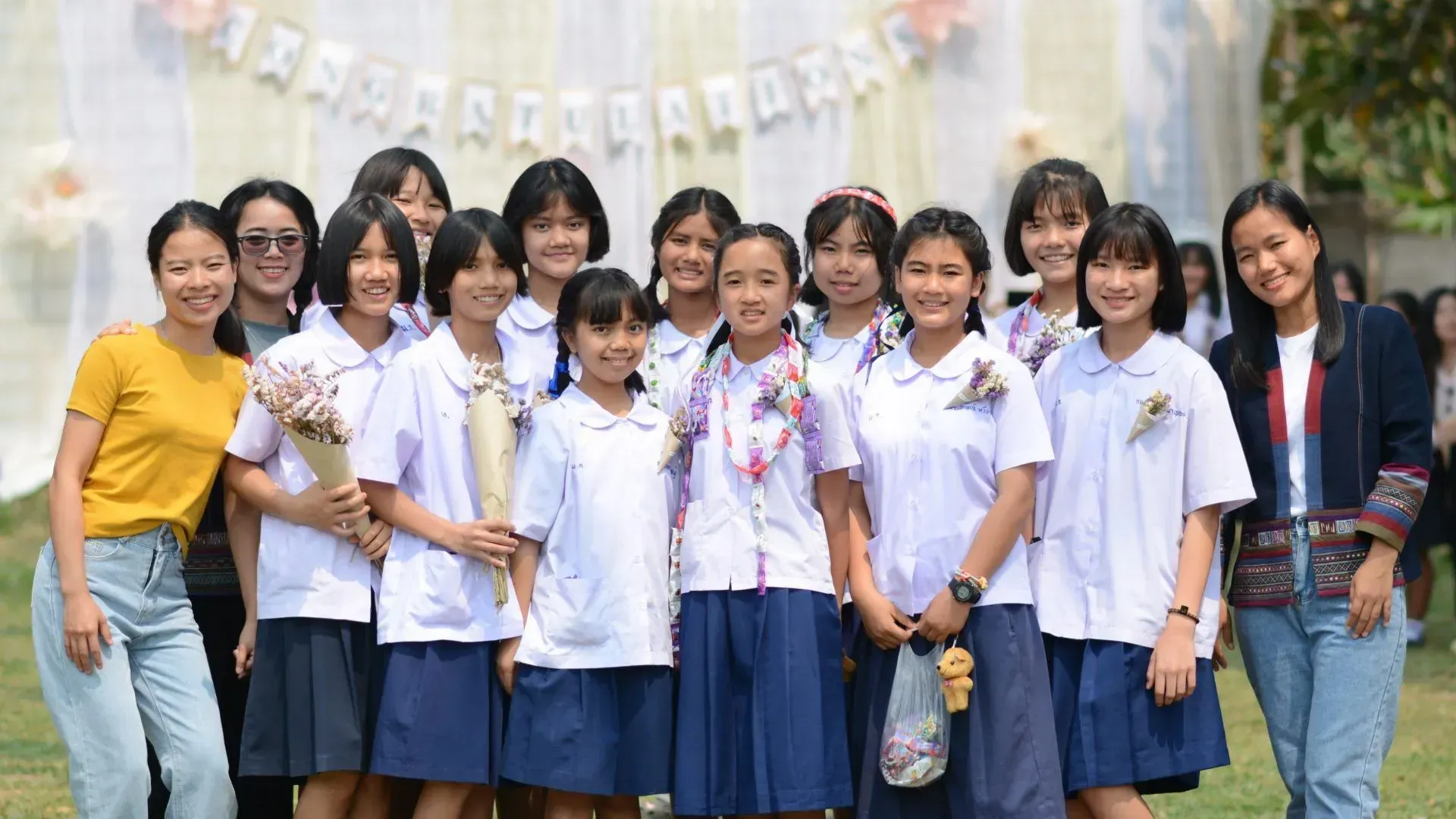 A group of young girls in school uniforms are posing for a picture.