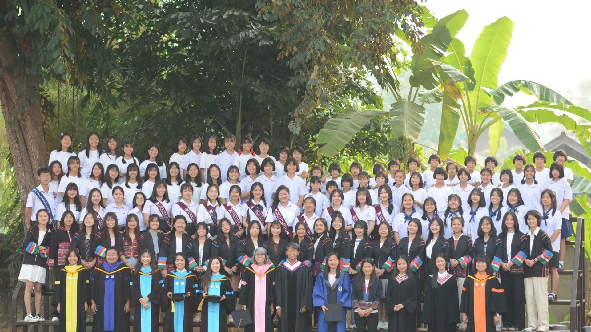 A large group of people are posing for a picture in front of trees.