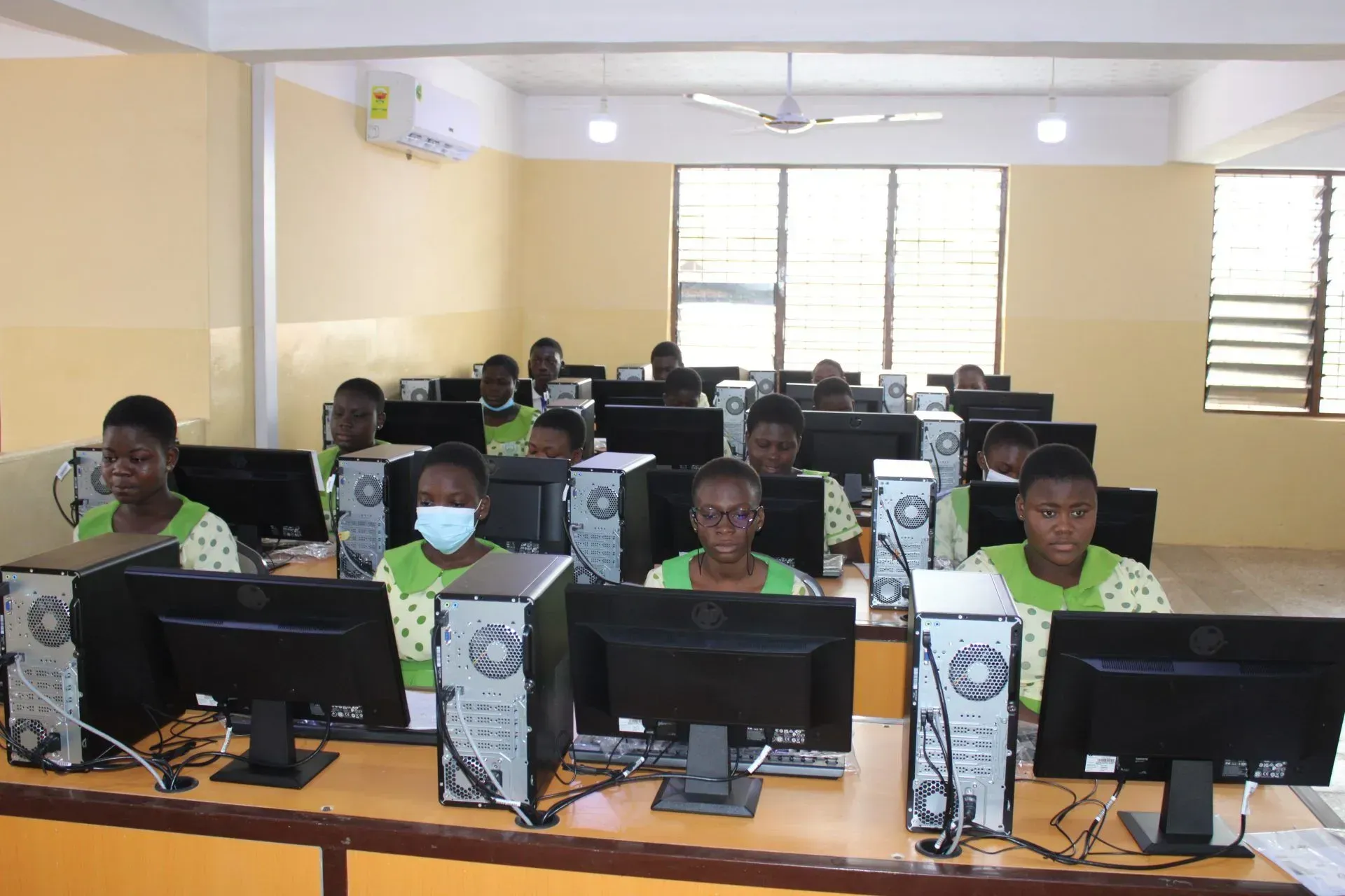 A group of people are sitting in front of computer monitors in a computer lab.