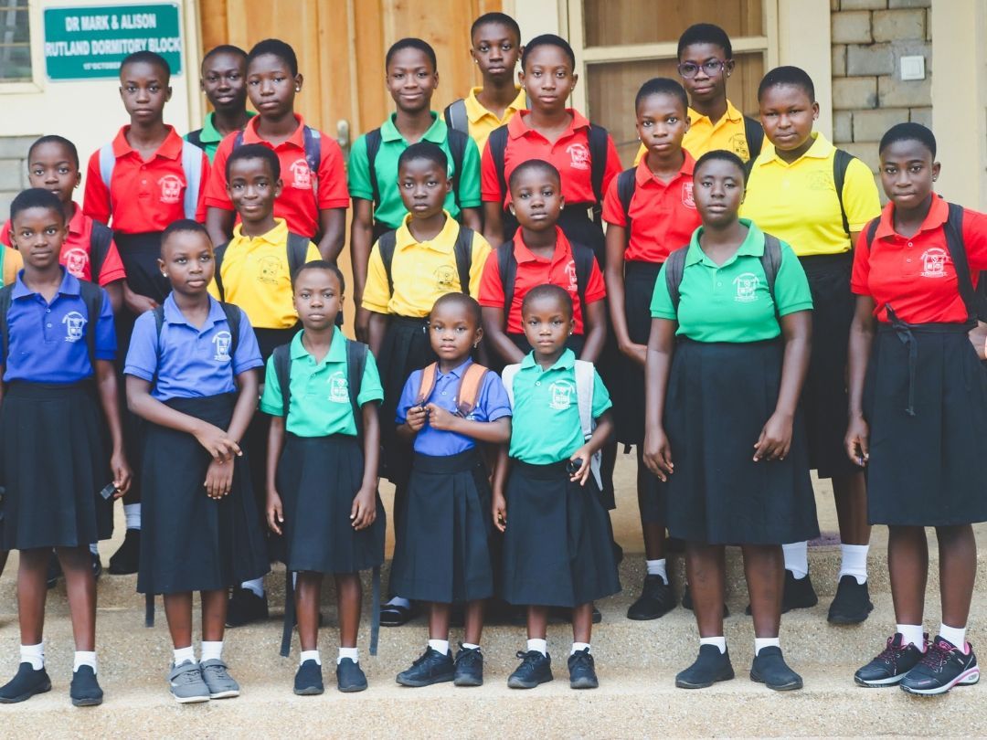 Group of students in school uniforms posing outdoors on steps.