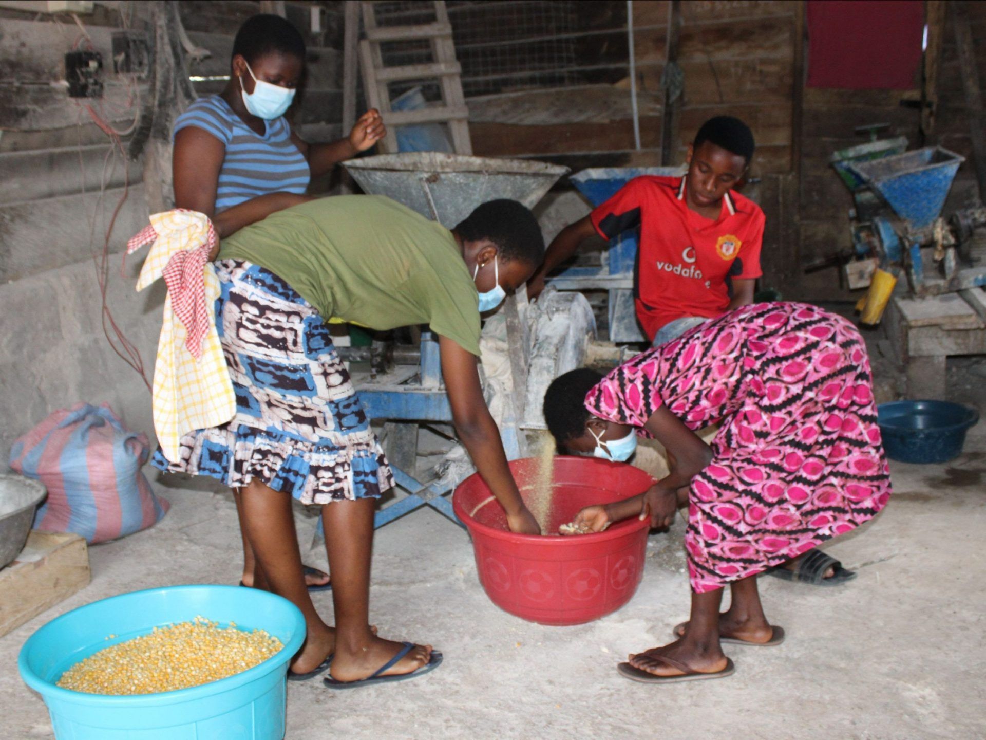 A group of people are standing around a bowl of food.