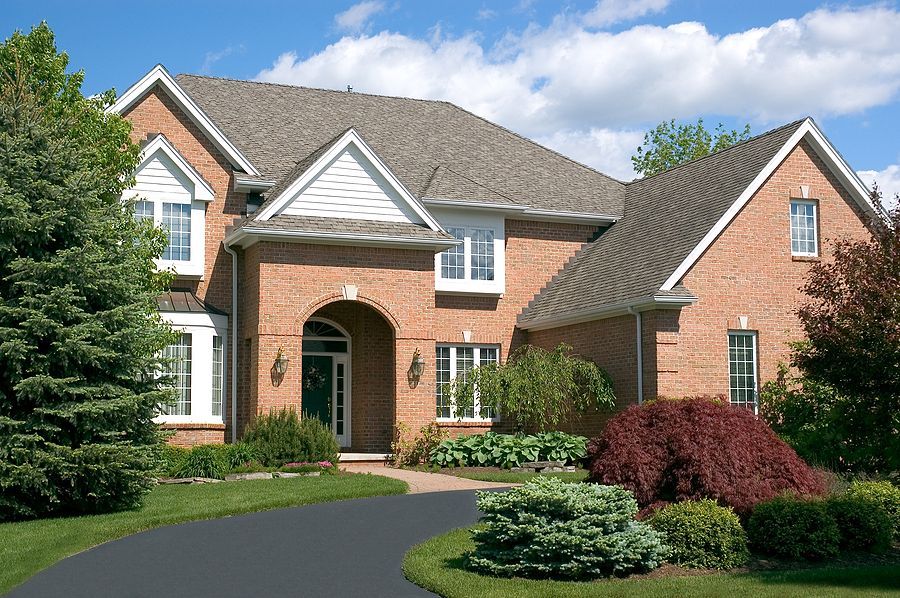 A red brick house with a black resin driveway by Cambridge Resin Driveways