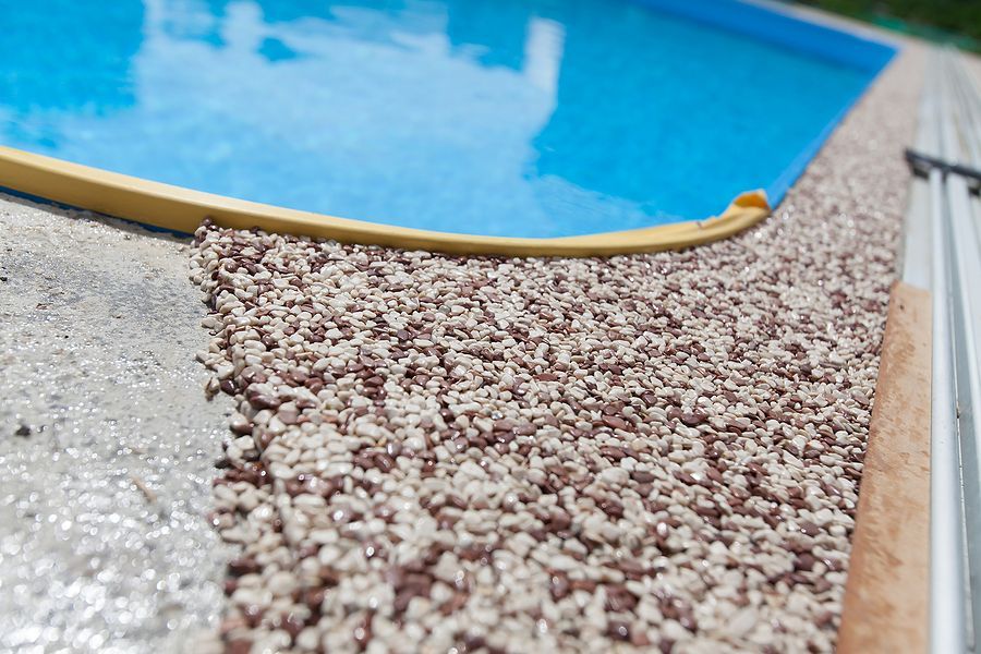 A swimming pool is surrounded by gravel and concrete
