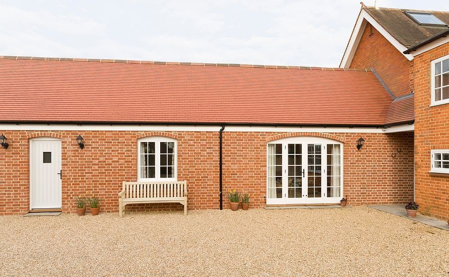 A brick house with a red roof and white windows
