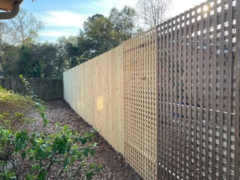 Long wooden fence in a narrow garden path with trees and shrubs beside it