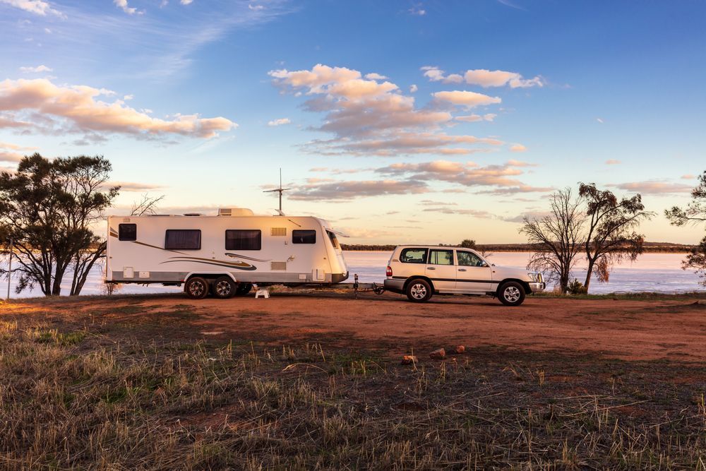 A Caravan Is Being Towed By A Car On A Dirt Road — Kingston Caravan Repairs In Heatherbrae, NSW