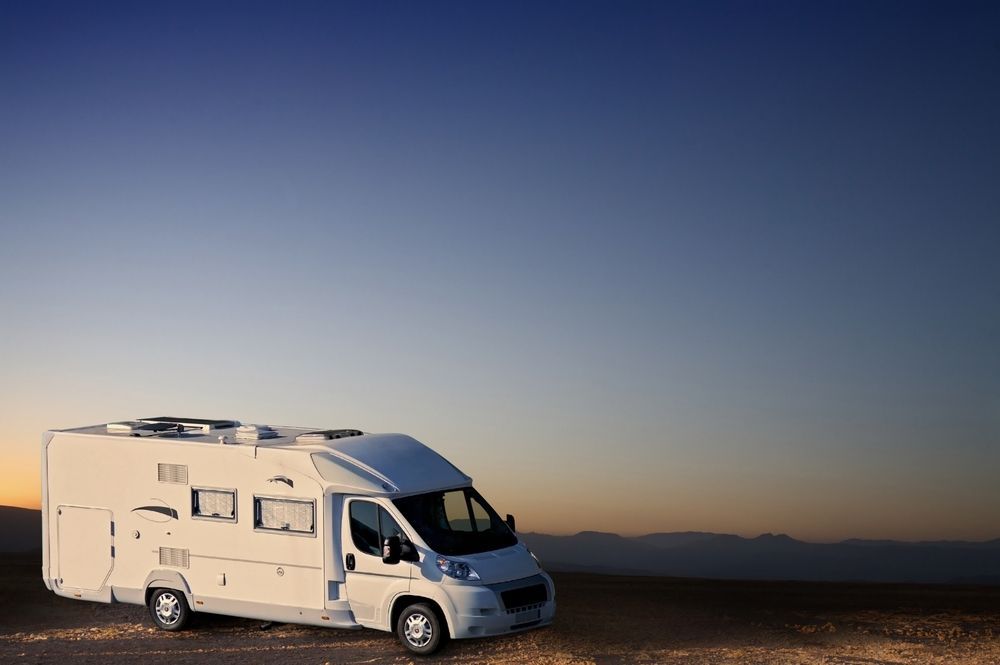 A White Caravan Is Parked In The Middle Of A Desert At Sunset — Kingston Caravan Repairs In Heatherbrae, NSW